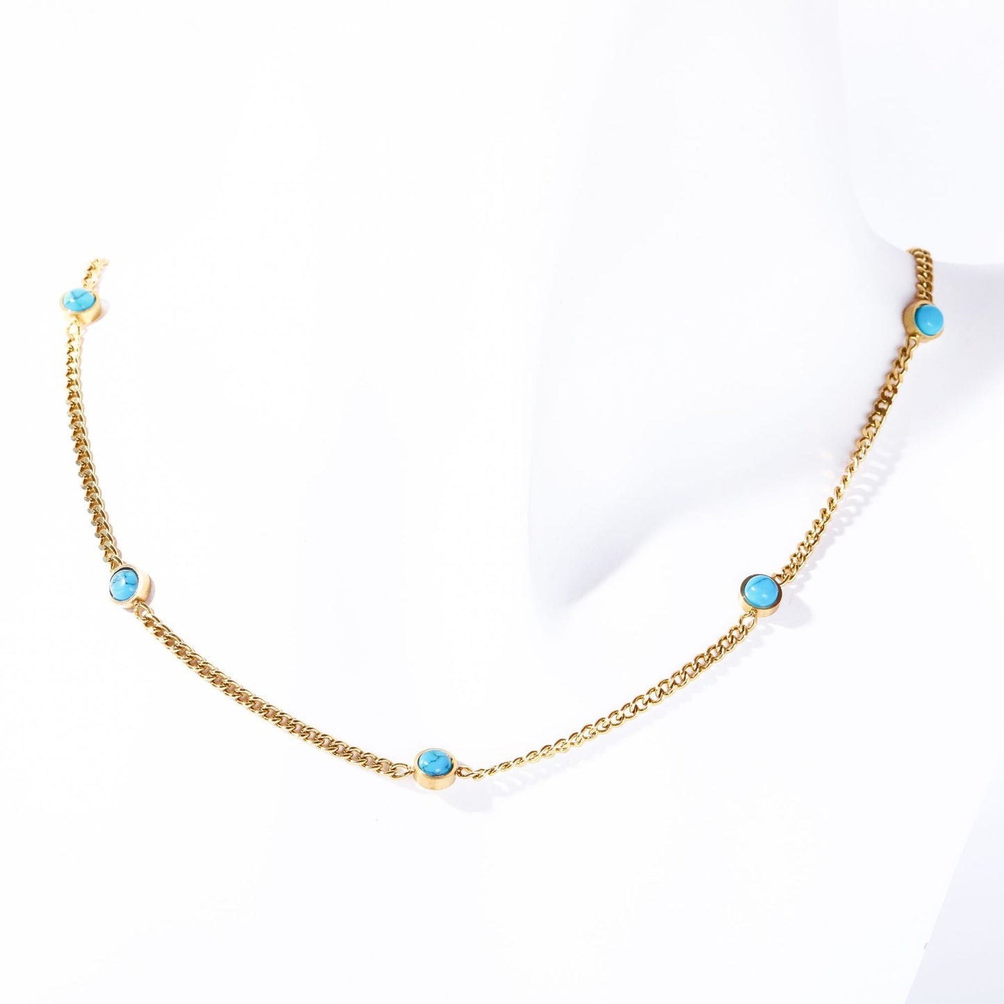 Gold electroplated turquoise necklace displayed on white fabric background