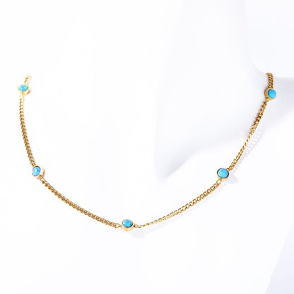 Gold electroplated turquoise necklace displayed on white fabric background