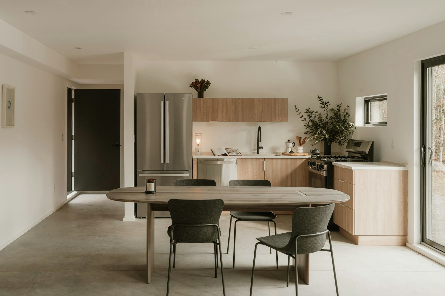 Bright open kitchen and dining room with a light oak table and soft natural daylight