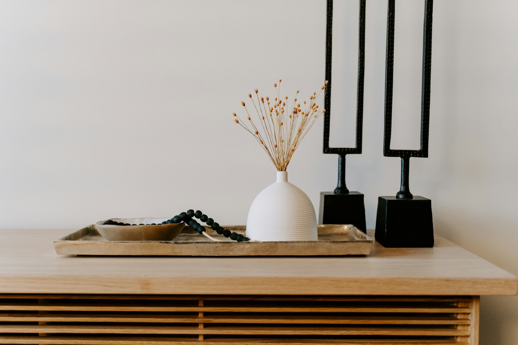White ceramic vase and black sculptural objects styled on a table