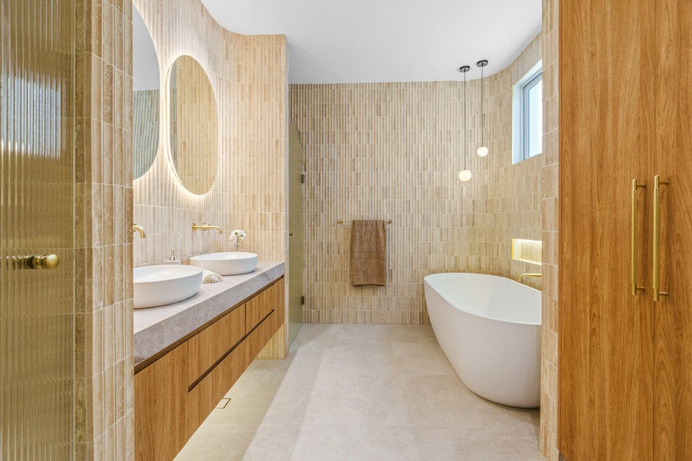 Bathroom with double sinks, a freestanding tub and wooden accents