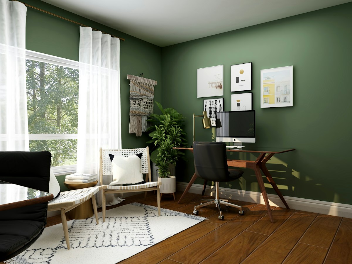 Home office with green walls, a wooden desk and a black chair