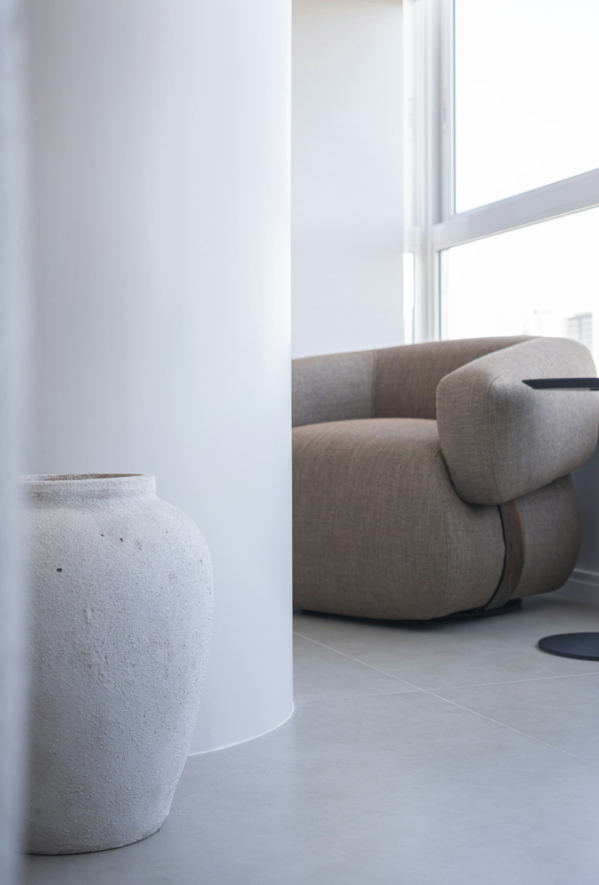 Modern lounge armchair beside a large floor vase in a bright room