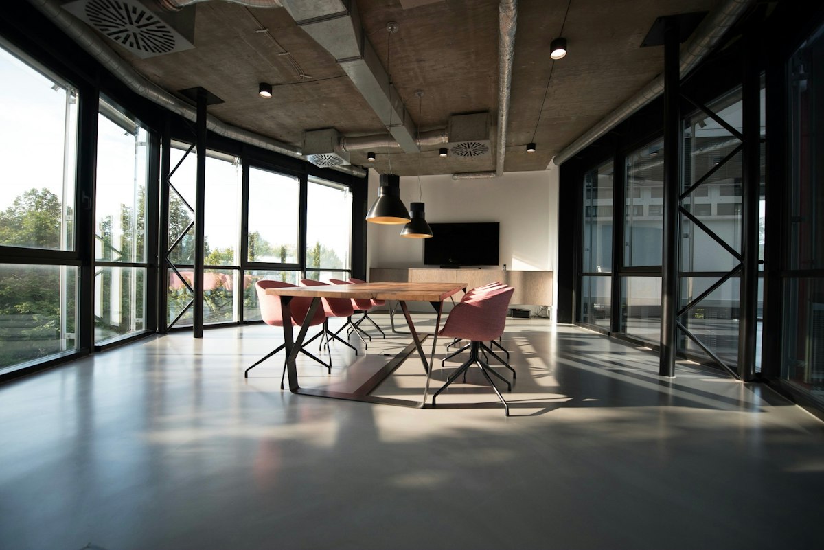Open-plan workplace with a long shared table and pendant lighting