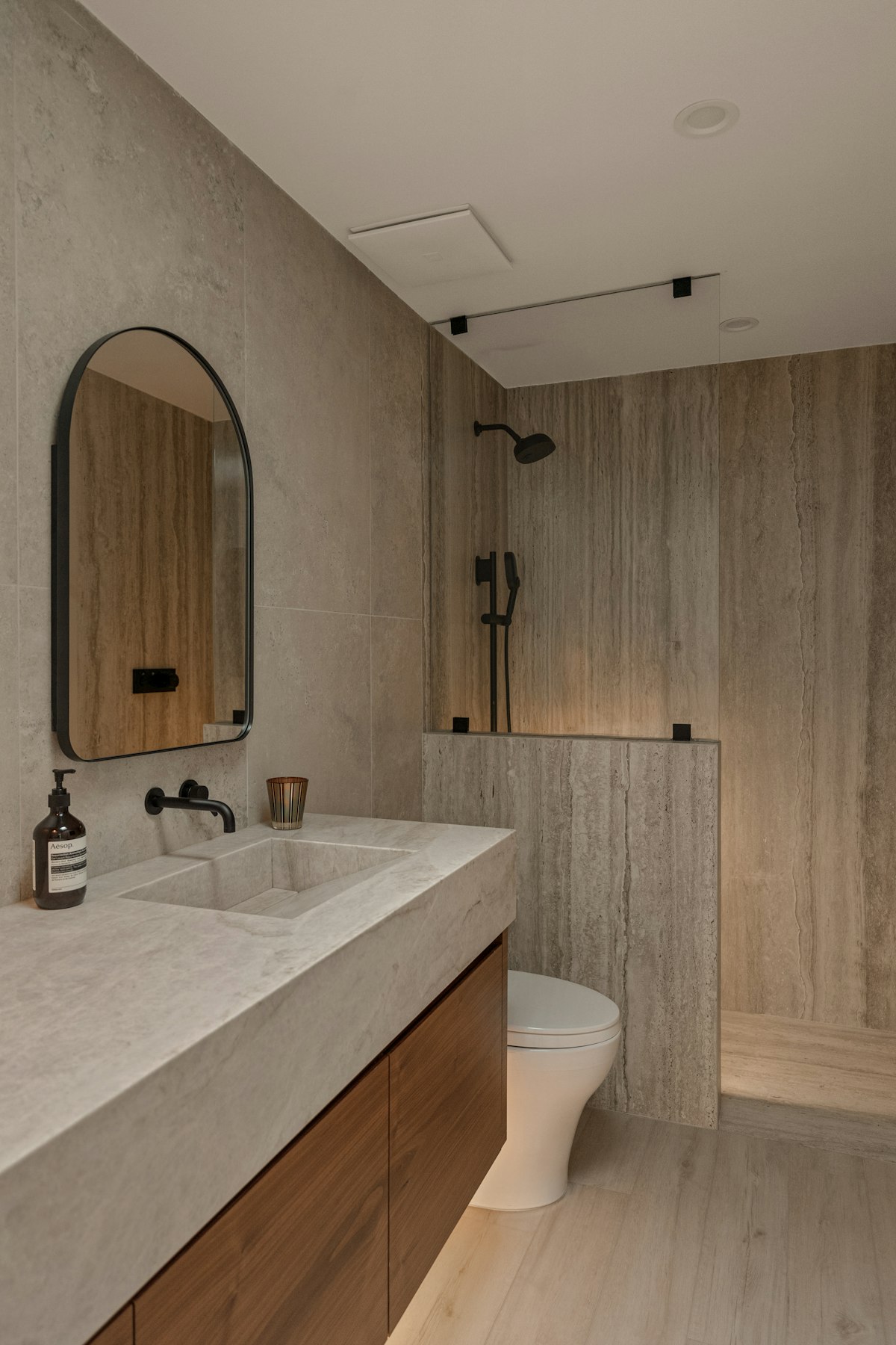 Calm bathroom with stone wall tiles, a wooden vanity and a freestanding tub