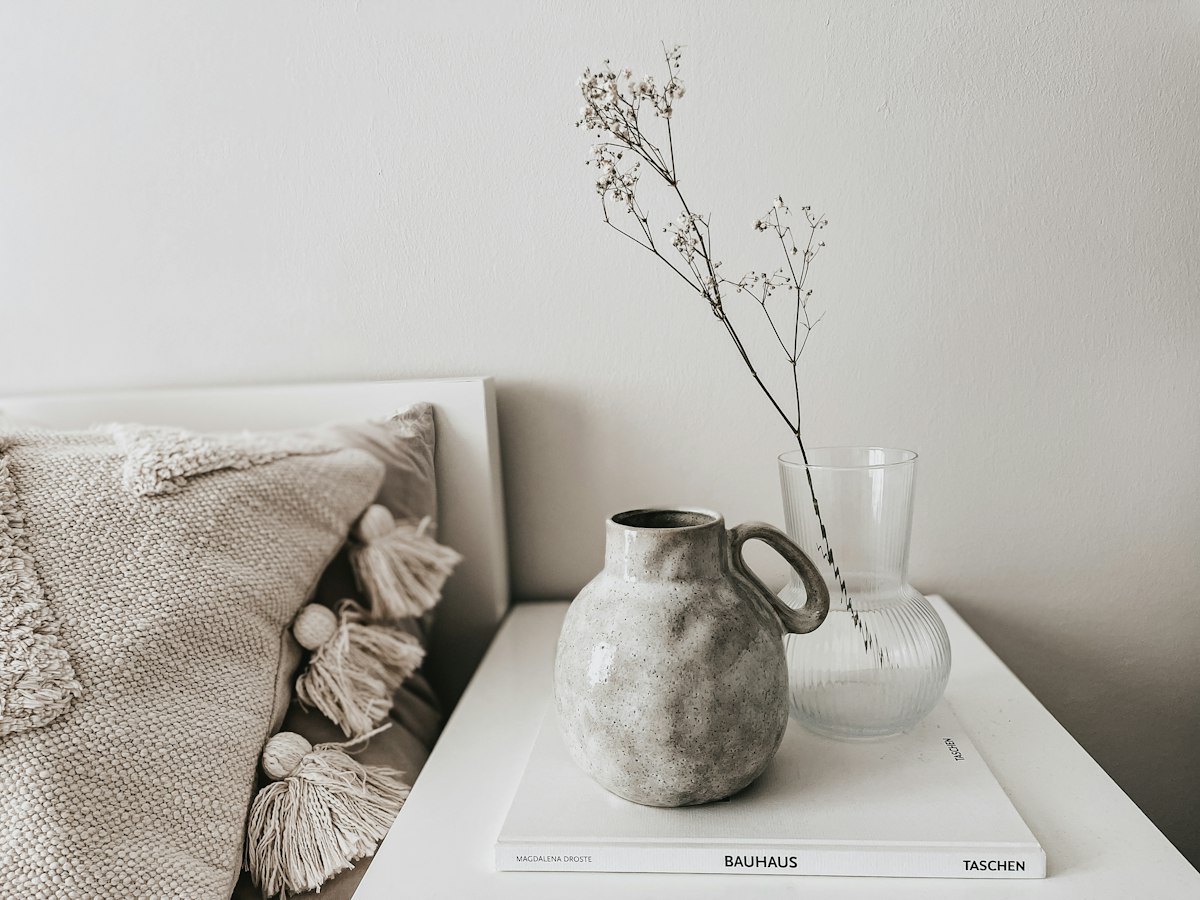 White ceramic vase resting on a stack of white books
